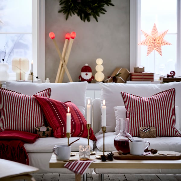 Trois housses de coussin VINTERFINT à rayures rouges sont posées sur un canapé dans un salon décoré pour Noël.