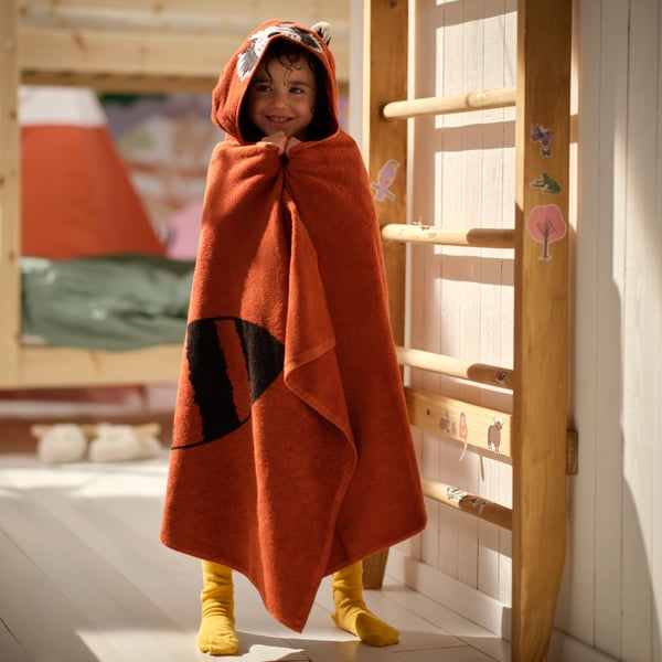 A child dries off with a cotton ALPTALL red panda towel with hood after a bath.