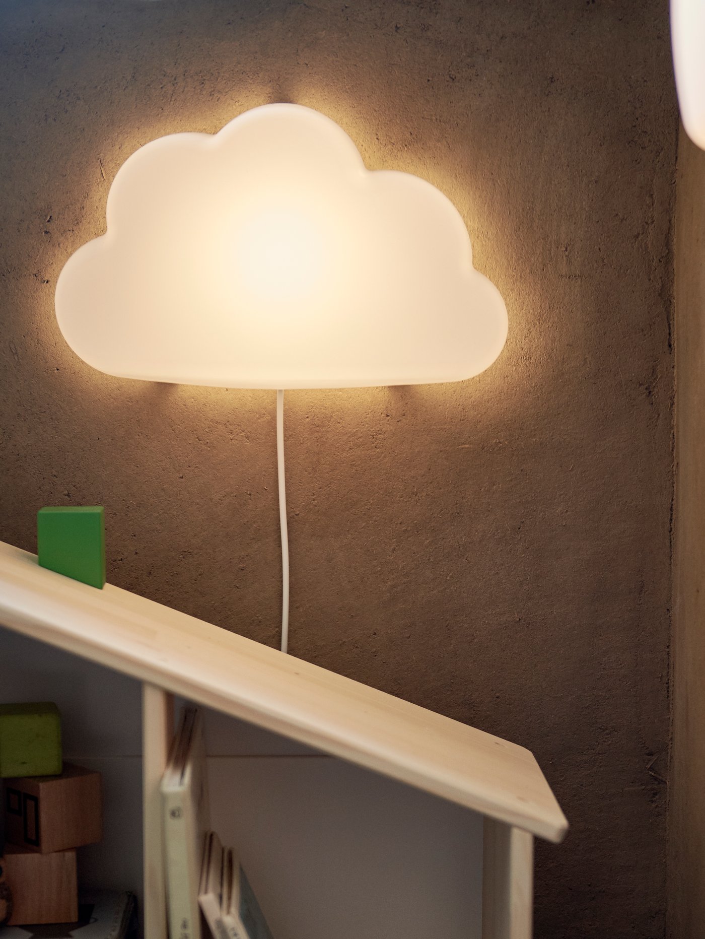 A cloud night light hanging on a wall above a slanted shelf