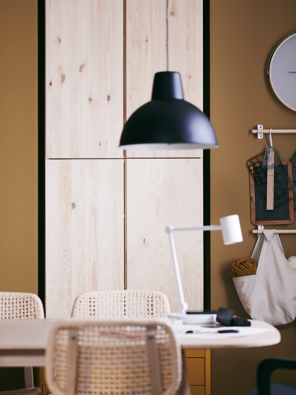 Wall-mounted IVAR cabinets in pine providing generous storage in a combined dining and workspace area with table and chairs.