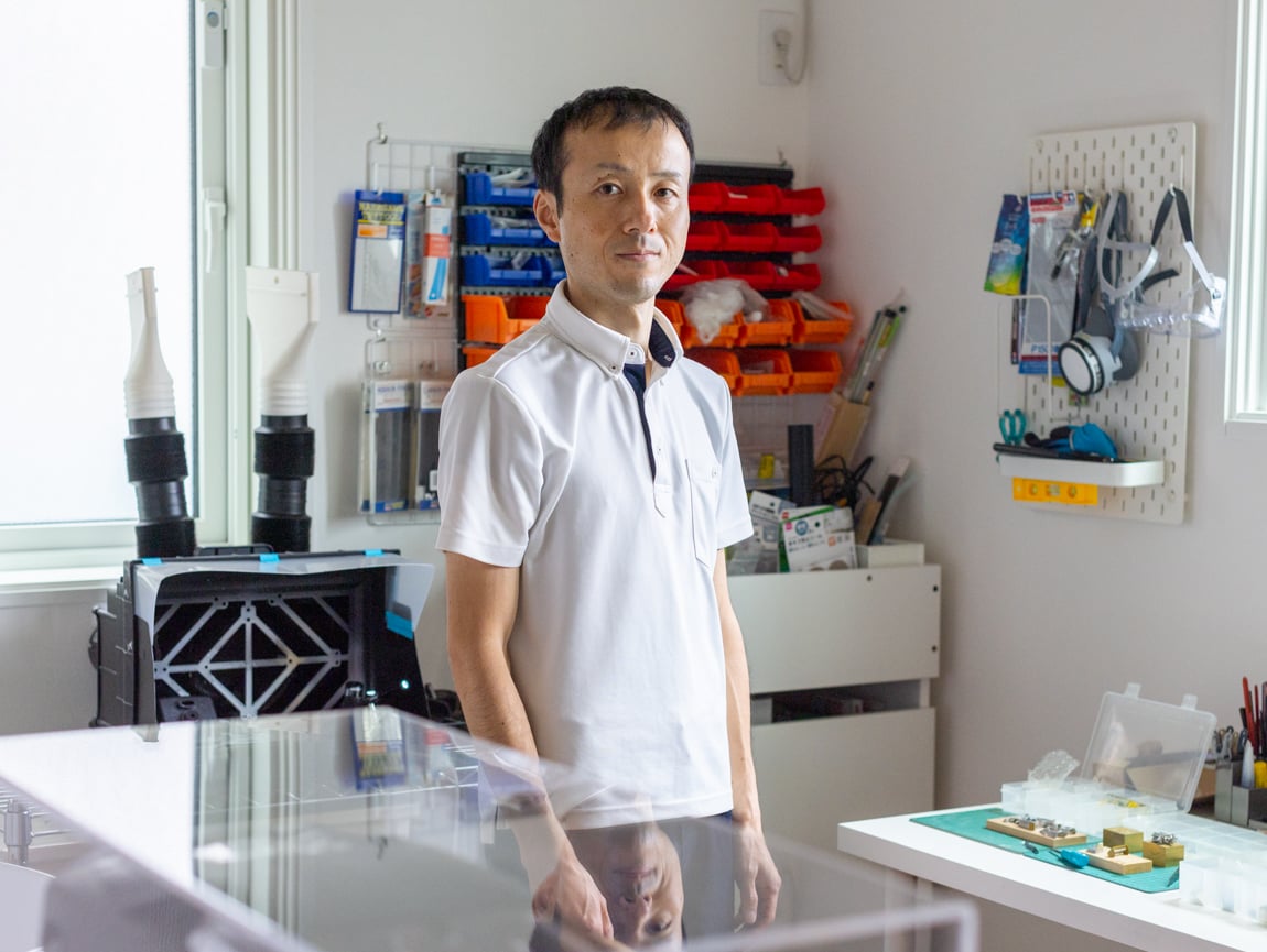 Man standing in his office space, surrounded by well organised tools and items.