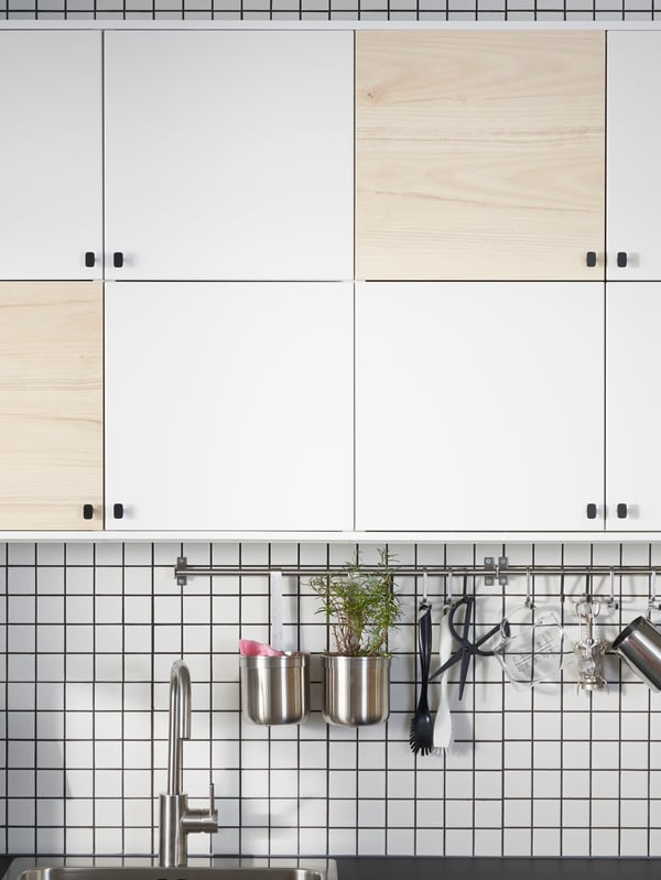 Cabinets on a kitchen wall with six doors in white and two doors in a light ash effect to make a pattern.