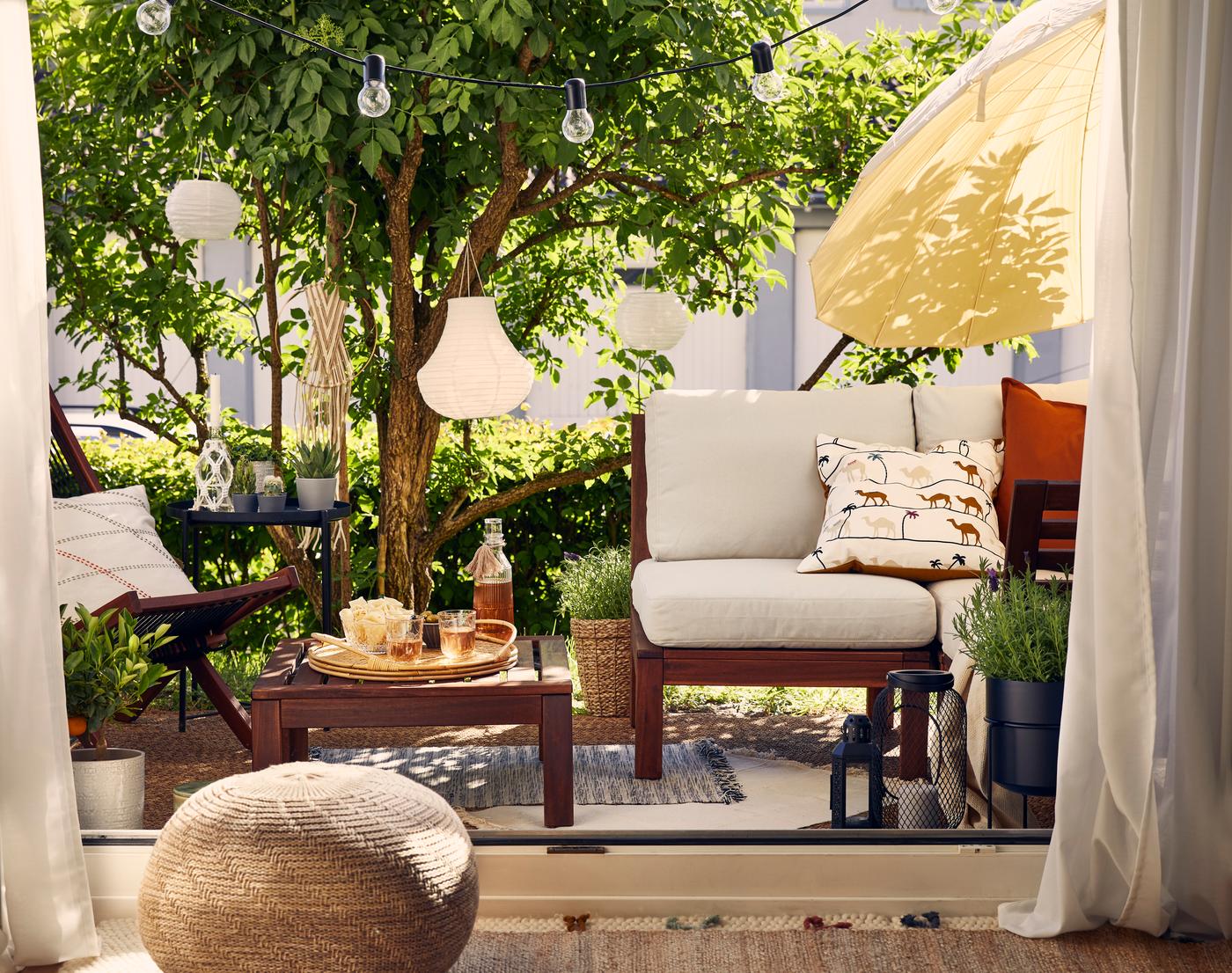 Gartenterrasse mit Lounge aus Holz, Lampions und Lichterketten