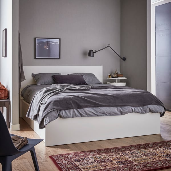 A white MALM bed frame with gray bed linen