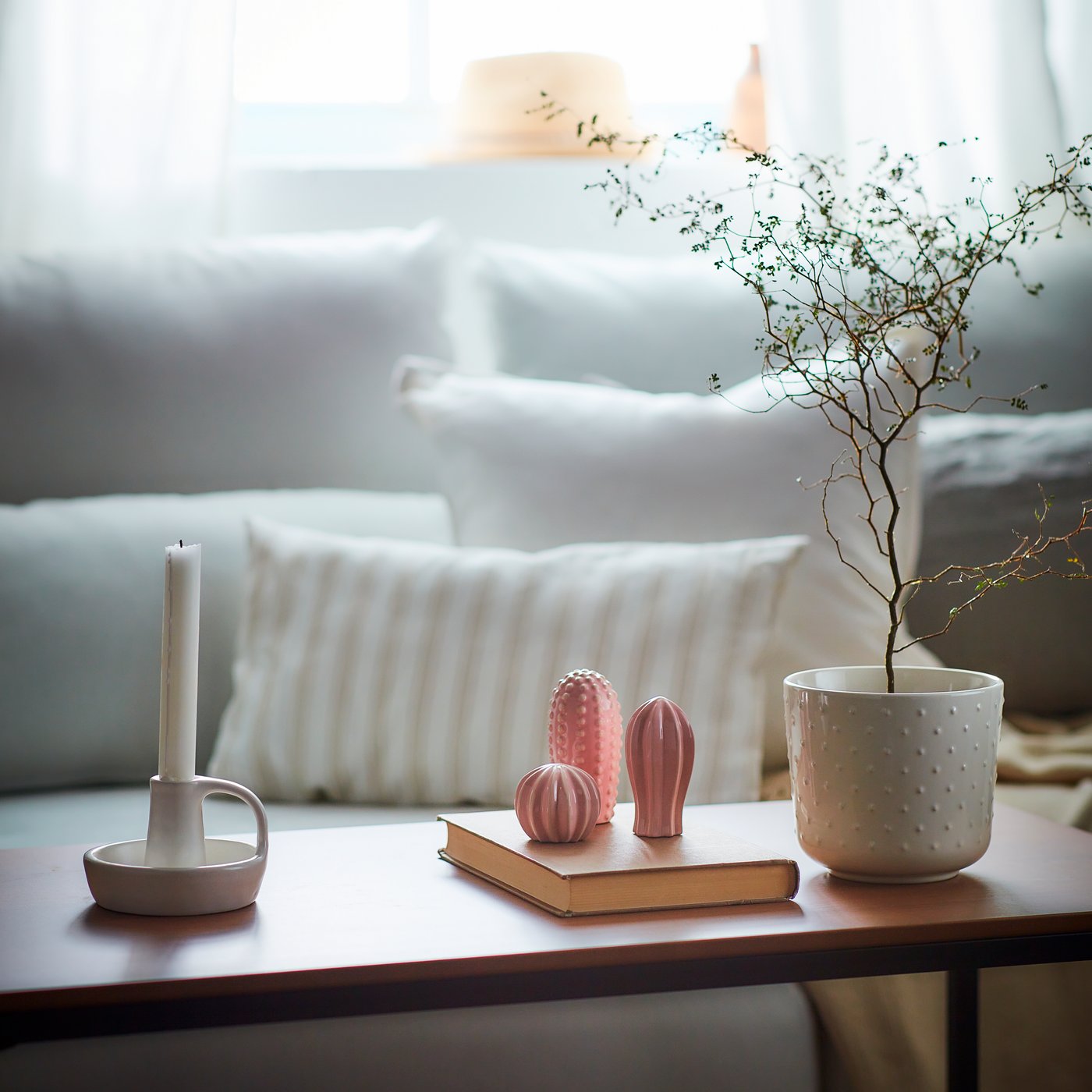 Dekoration auf einem Tisch und im Hintergrund ein weißes Sofa mit weißen Pölstern
