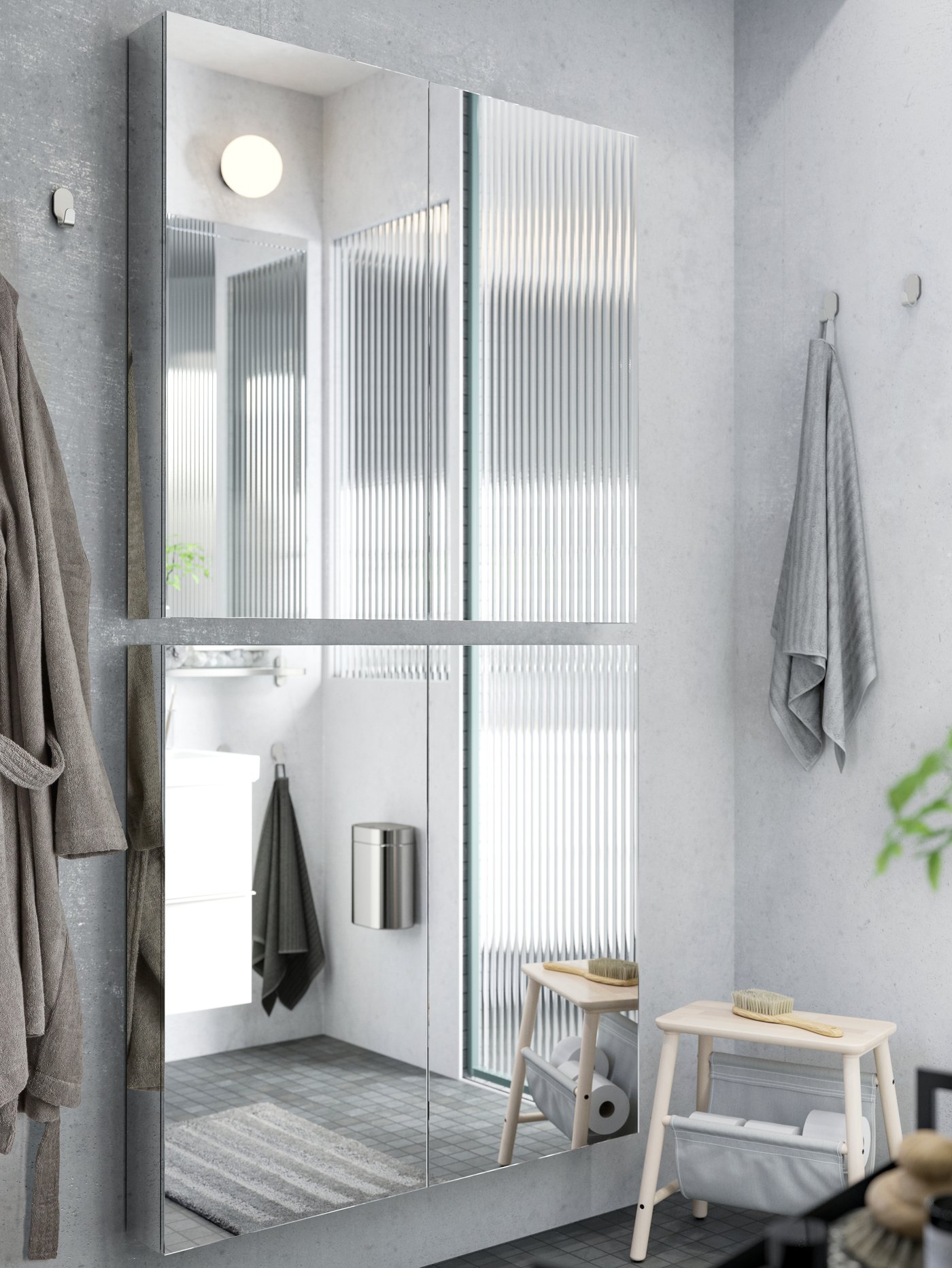 Deux meubles à miroir GODMORGON avec portes sont installés l’un au-dessus de l’autre sur un mur de salle de bain gris clair.