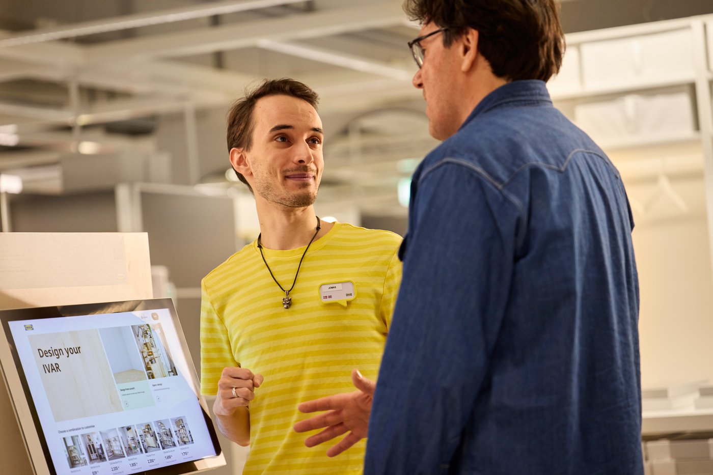 IKEA zaposleni u robnoj kući pokazuje kupcu kako da dizajnira IVAR sistem na ekranu.