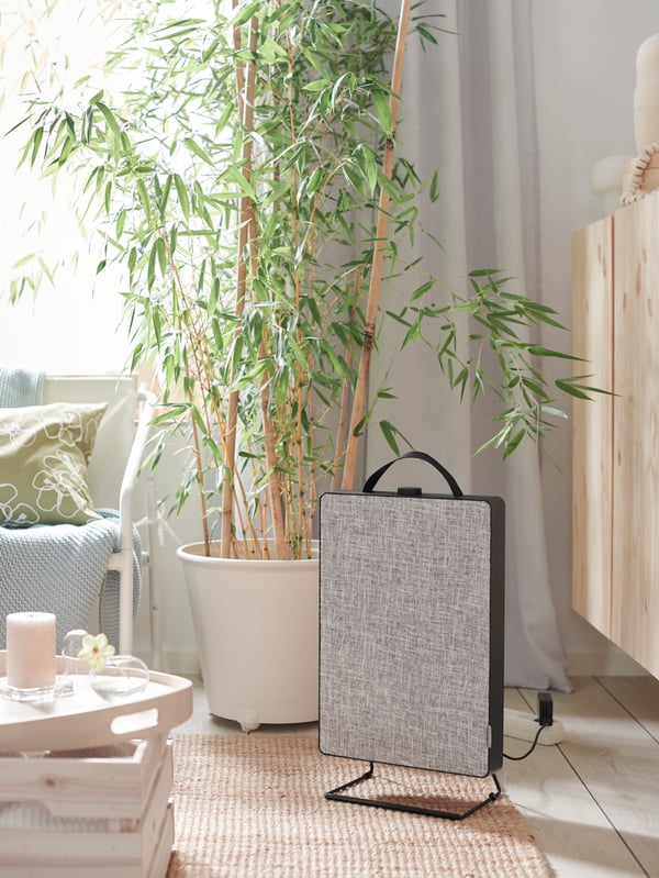 Une personne en jeans bleu et T-shirt blanc tient un mug rose et est assise sur un tabouret assis/debout LIDKULLEN.