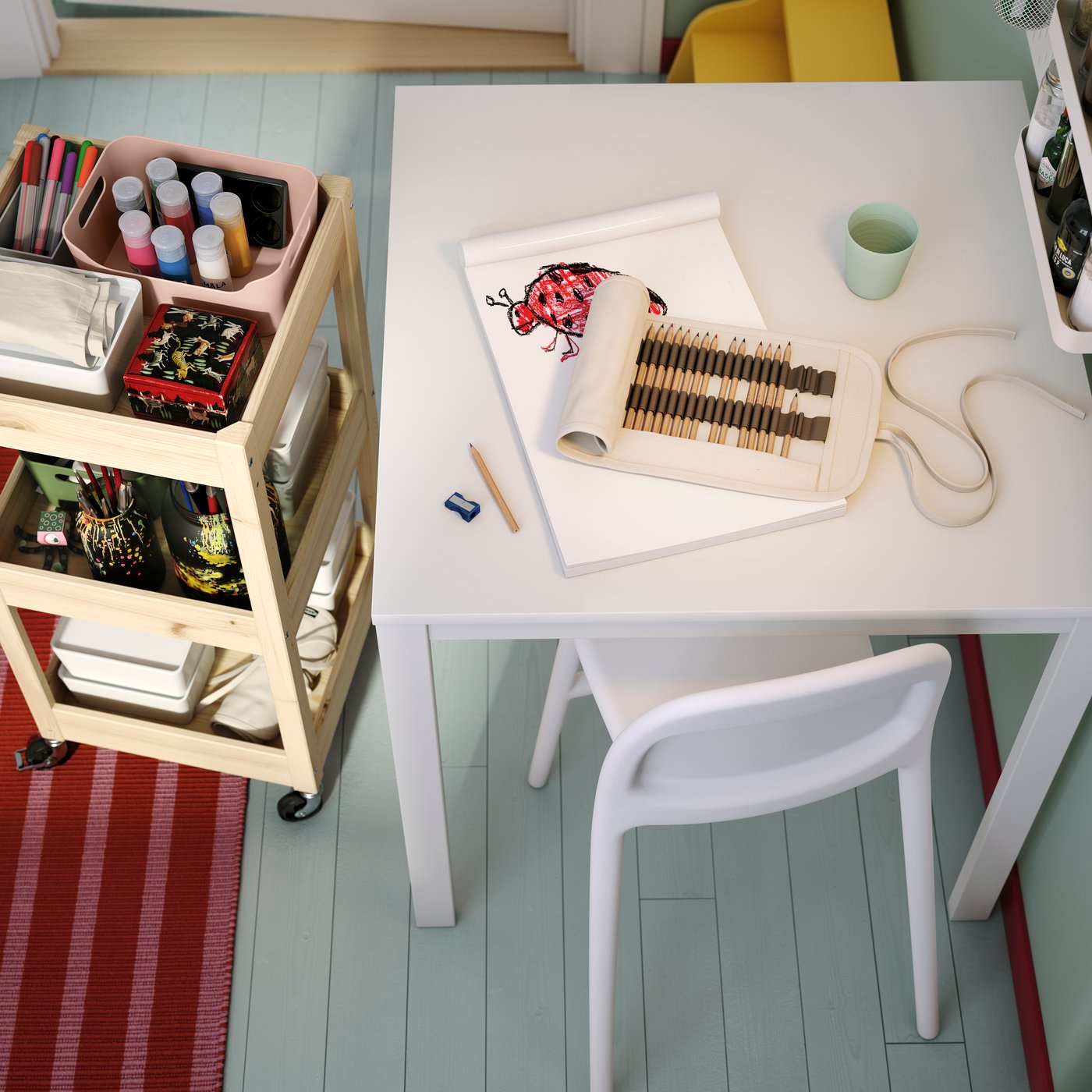 A white VIHALS table surrounded by a chair and crafting supplies on a cart, set in a bright, organised workspace.