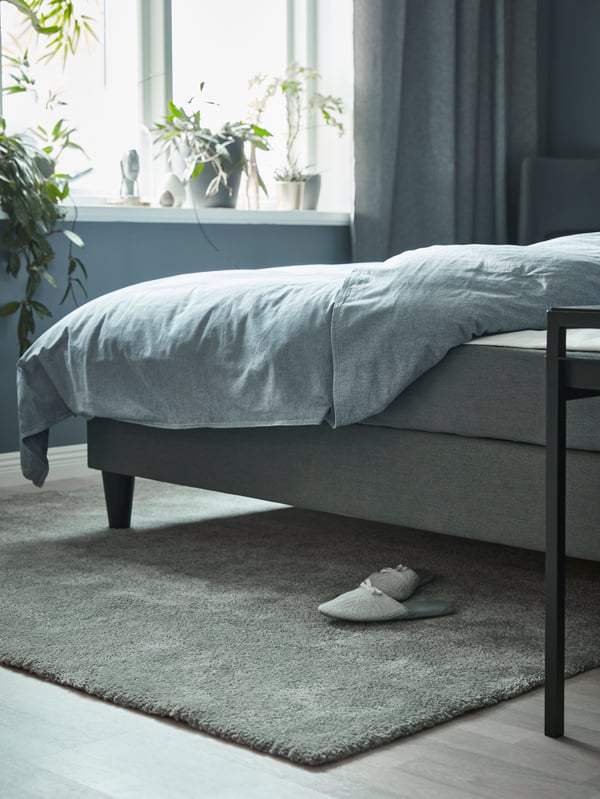 Et mellemgråt STOENSE tæppe med lav luv i soveværelset