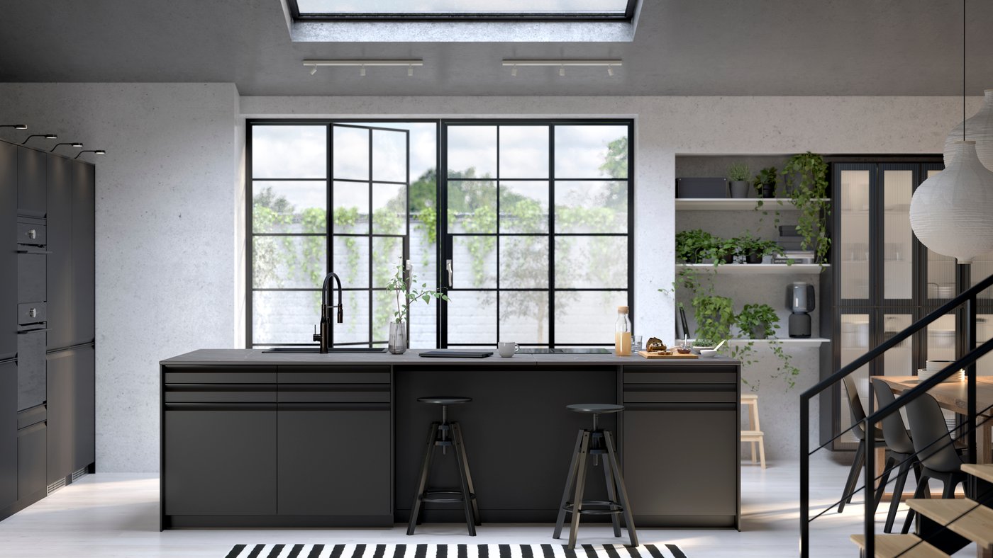 Schwarze Industrial Style Küche in einem modernen Loft. Küchenblock mit UPPLÖV Fronten in Anthrazit, DALFRED Barhockern in Schwarz und einem FÖRDELAKTIG Induktionskochfeld mit Dunstabzug.
