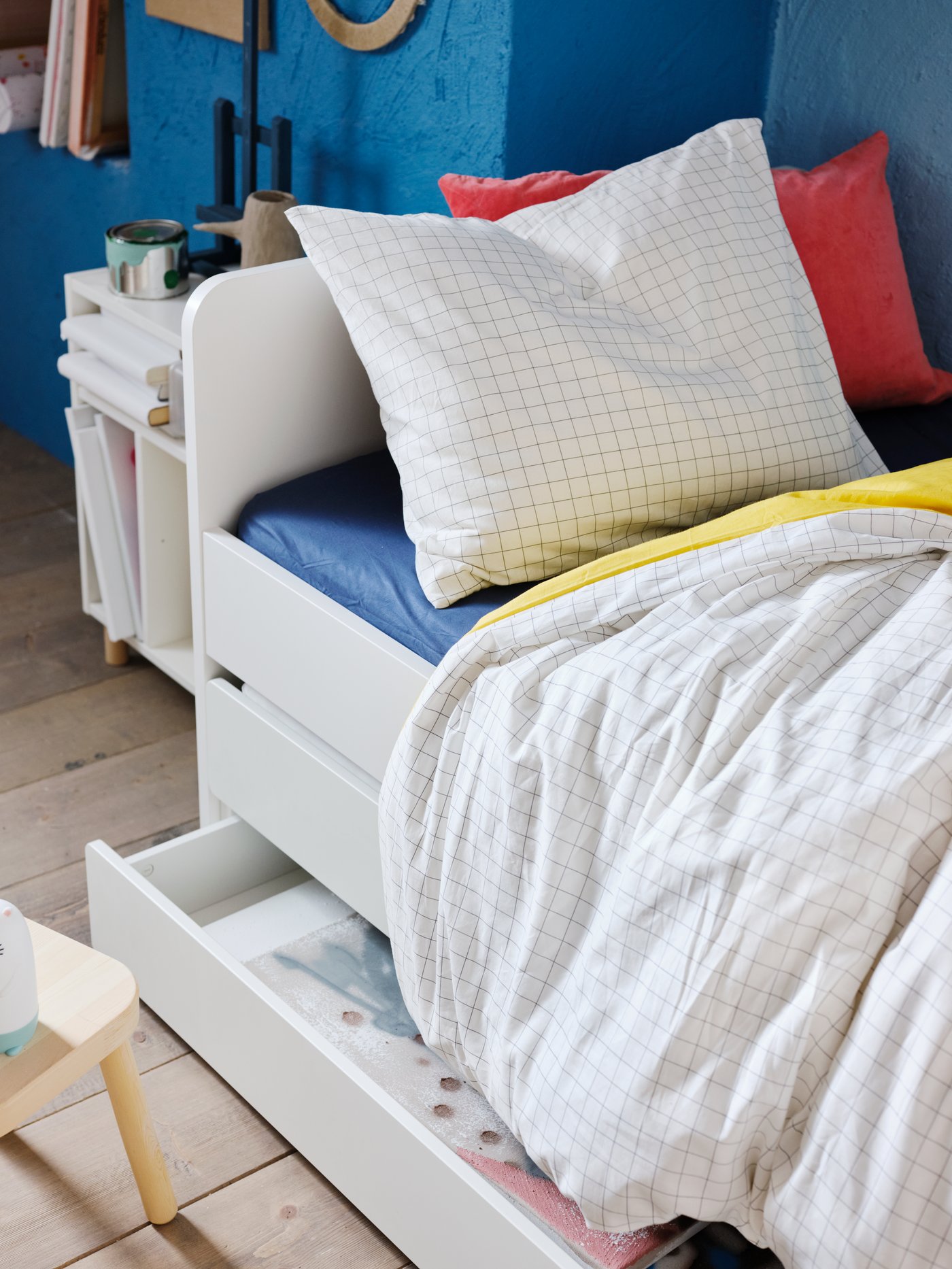 Una habitación infantil con una cama con almacenaje. La ropa de cama y los cojines son colorios al igual que las paredes.