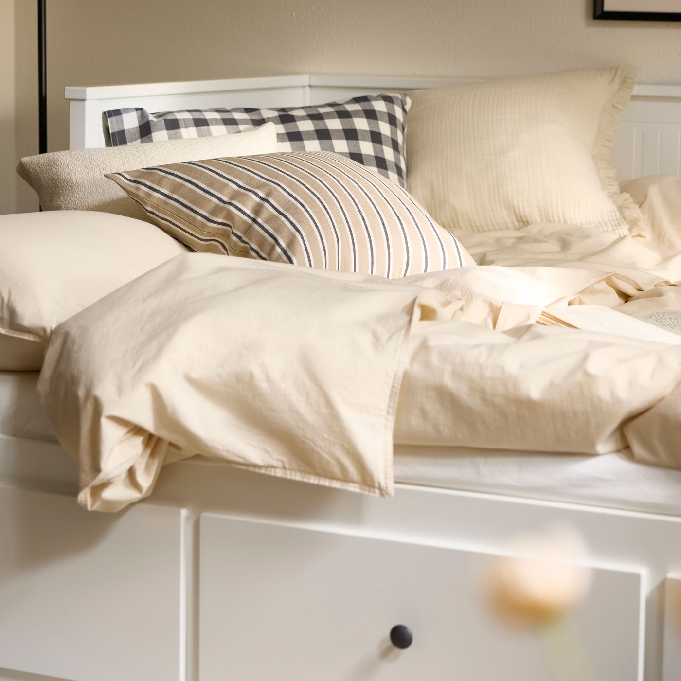 HEMNES daybed er indrettet som en dobbeltseng med ufarvet naturfarvet ÄNGSLILJA sengetøj ovenpå og en stribet hynde.