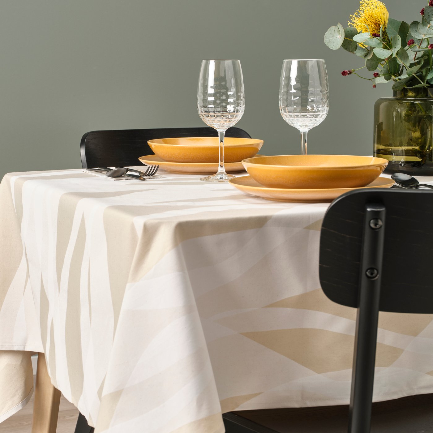 Eine weiß beige gemusterte KRUSTISTEL Tischdecke auf einem gedeckten Tisch.