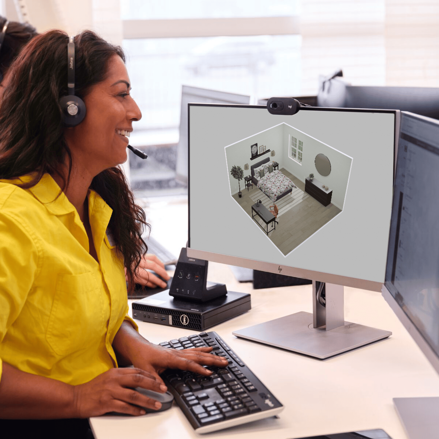An IKEA coworker sits at a desk on the phone to a customer, planning a bedroom
