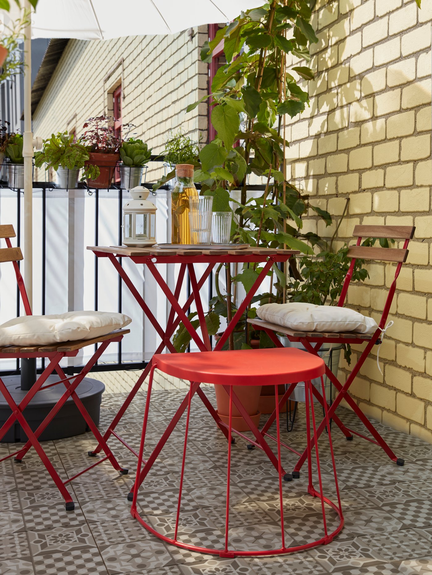 Un taburete/mesa auxiliar en rojo se encuentra junto a una mesa y sillas para ofrecer un asiento adicional cuando vienen invitados.
