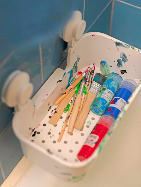 Pennelli e colori in un contenitore a ventosa applicato alle piastre della parete di un bagno.