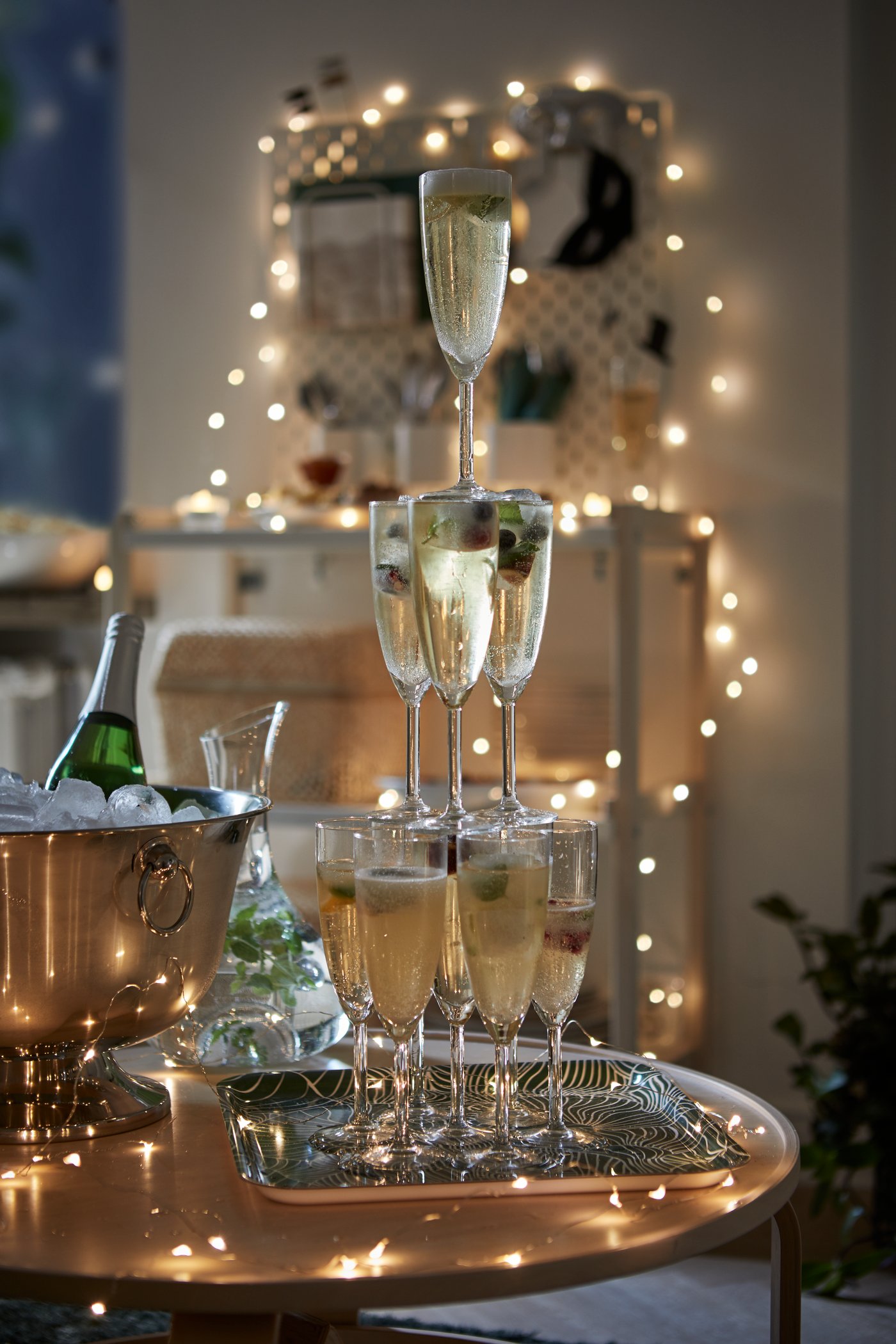 Ett torn av champagneglas med en ljusslinga i bakgrunden.