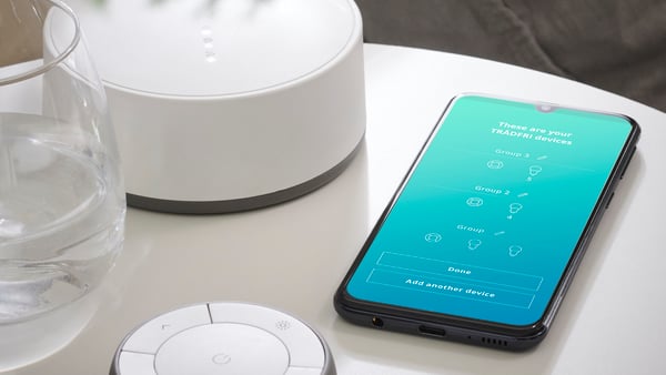 Trådfri mrežni prolaz na stolu pored mobilnog telefona na čijem se ekranu vidi otvorena aplikacija IKEA Home Smart 1.