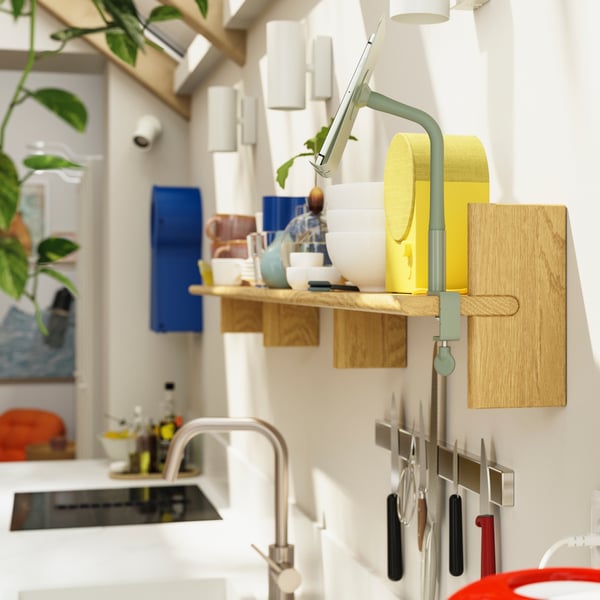 Une enceinte Bluetooth NATTBAD est posée sur une étagère murale KLAVRESTRÖM en chêne massif fixée au mur de la cuisine.