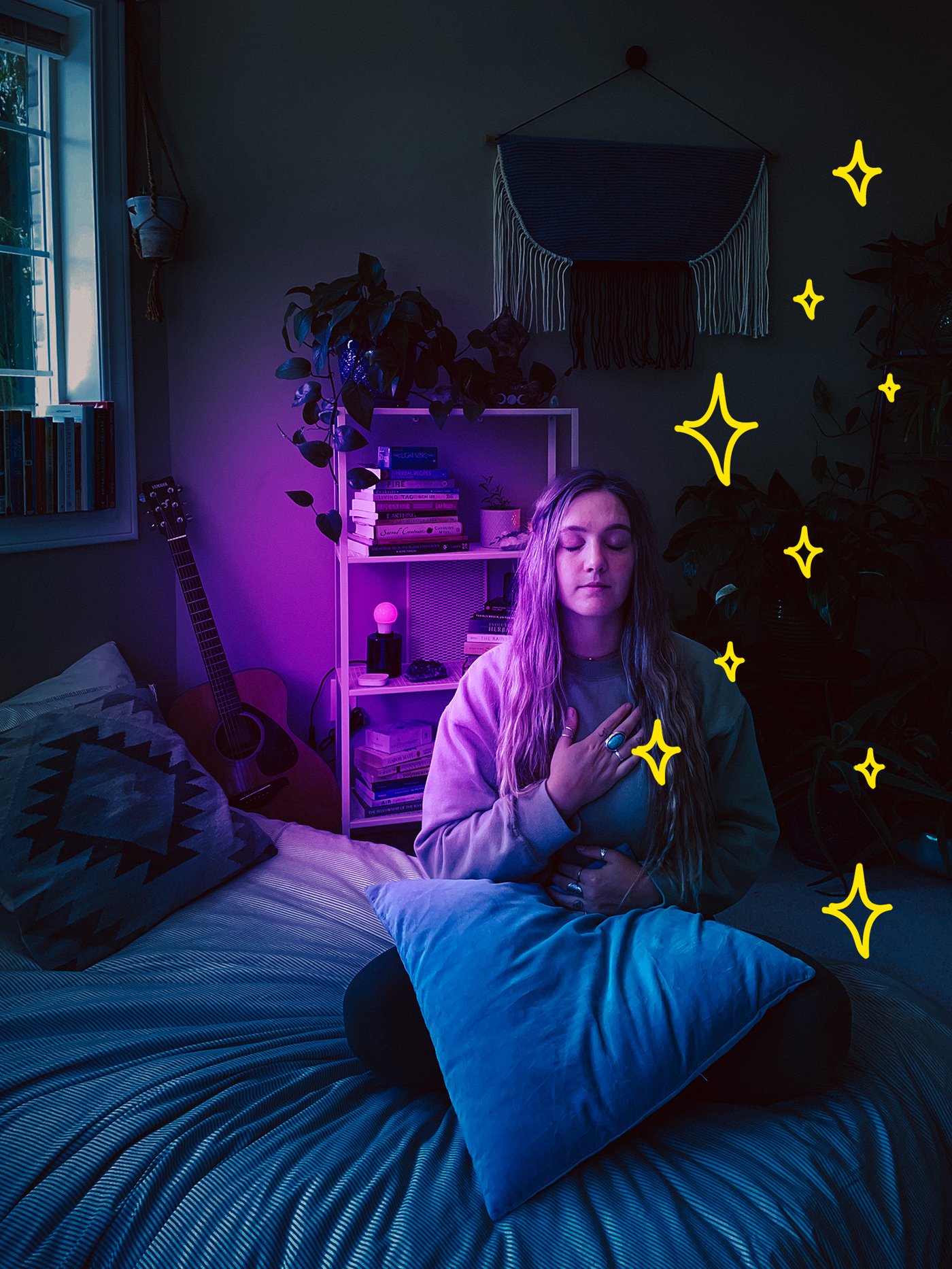 A woman relaxing on her bed, while the room is illuminated with purple-coloured lights.