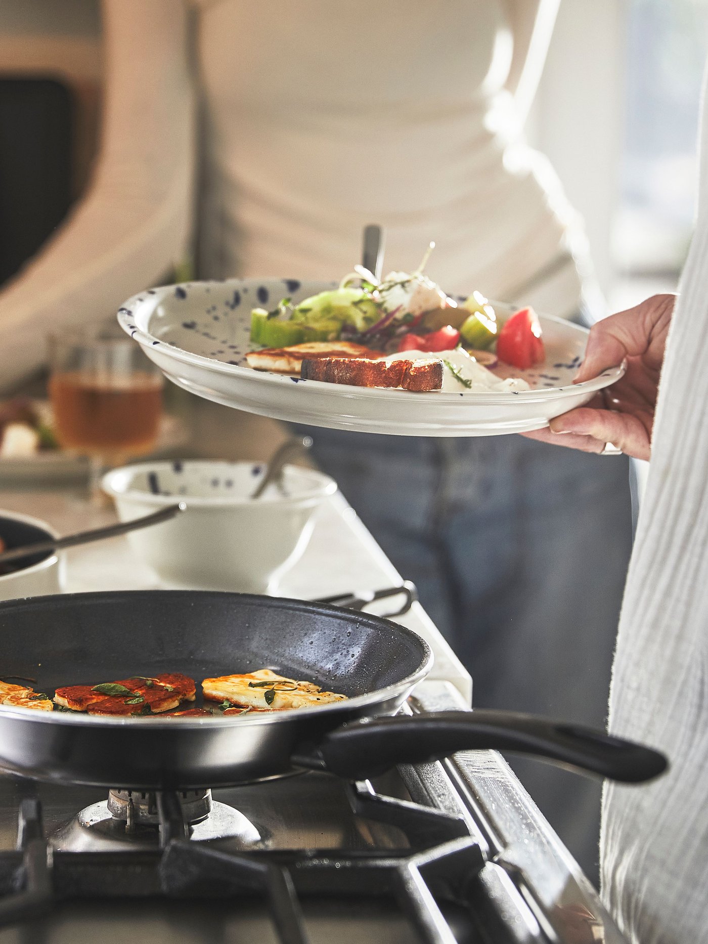 A person has just taken some fried food out of a black HEMLAGAD frying pan with non-stick coating and put it on a plate.