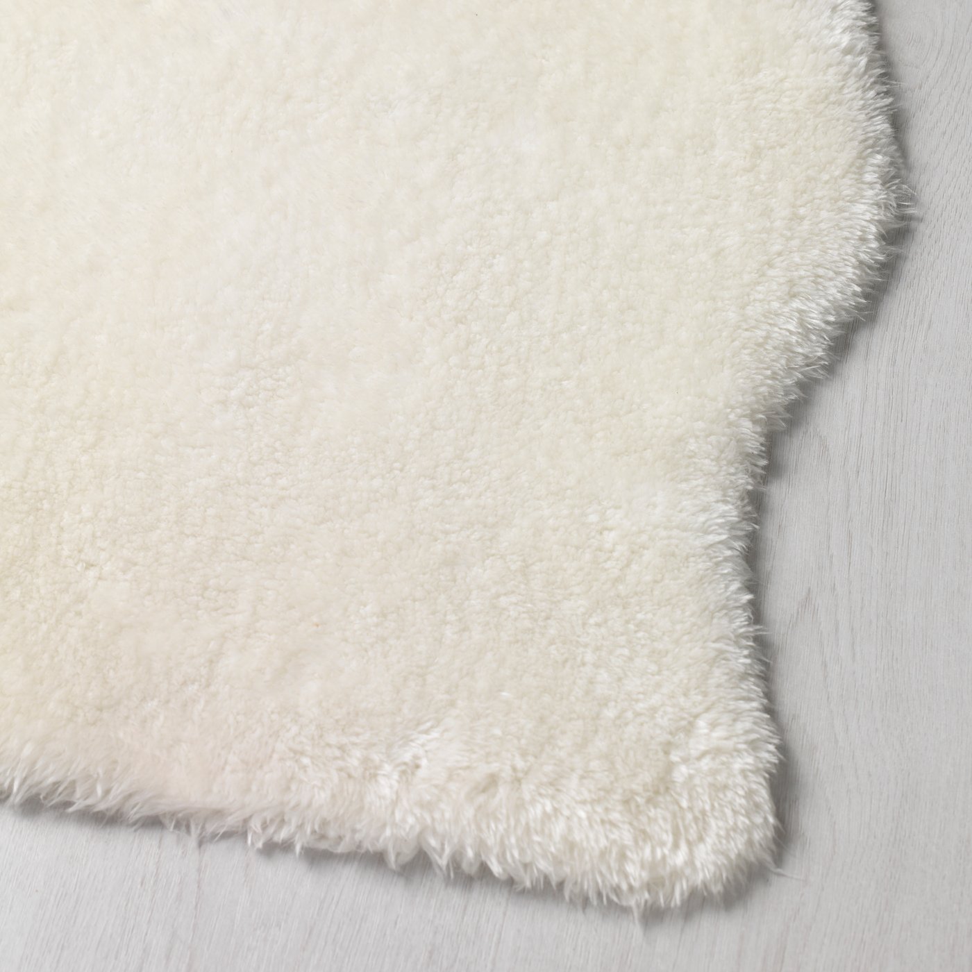 A close up of the faux sheepskin texture of a white TOFTLUND rug that is made from recycled polyester.