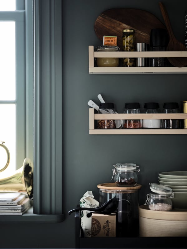 Una pared de cocina con repisas de madera BEKVÄM con condimenteros adentro.