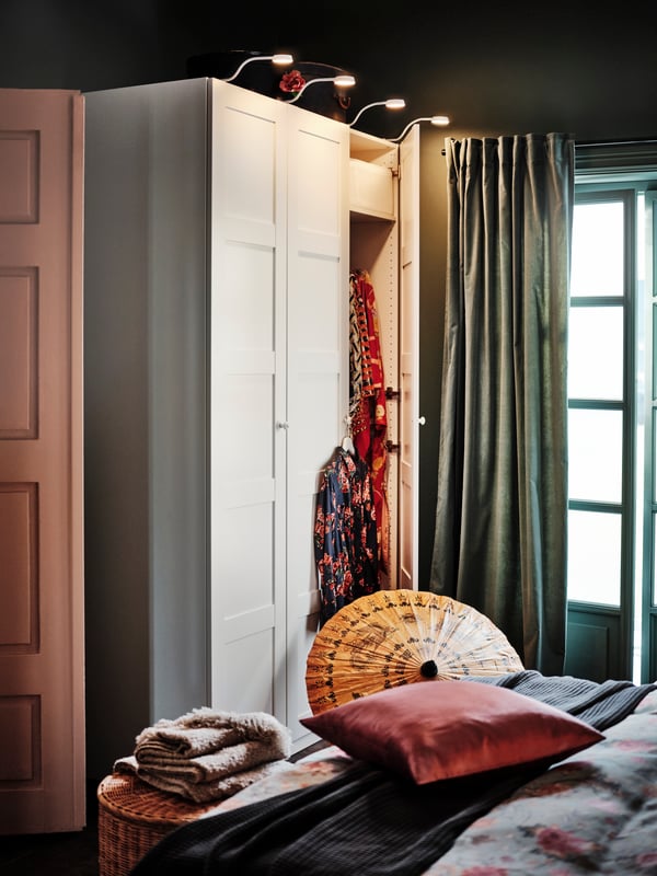 A PAX wardrobe with YTBERG cabinet lighting stands near a window with gray-green SANELA curtains.