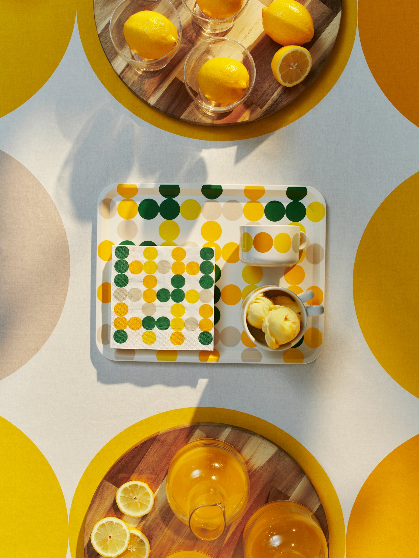 Chopping boards, carafes, dessert bowls with lemons, a tray, paper napkins and a tablecloth, all from BRÖGGAN collection.