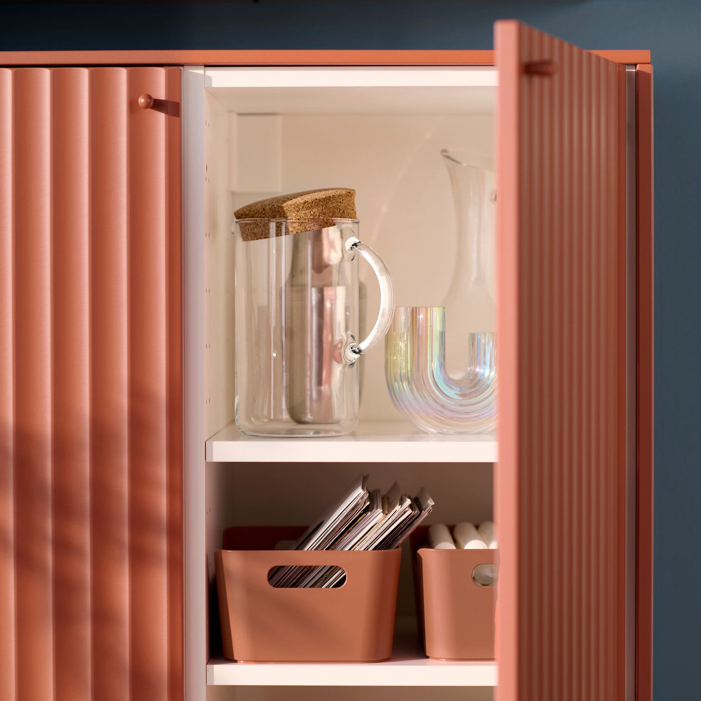 Un meuble de cuisine modulaire SEKTION avec une porte ouverte, laissant entrevoir des articles liés au repas rangés sur des étagères.