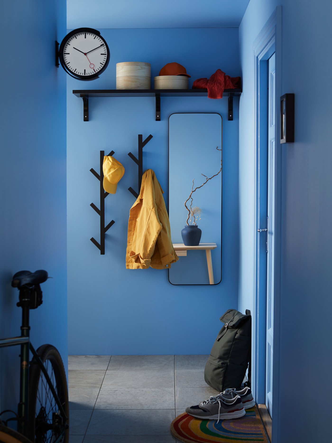 Un pasillo de una casa con un espejo de cuerpo completo y ganchos para colgar ropa.