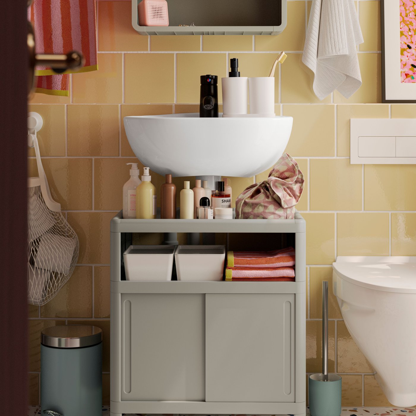 A green IVÖSJÖN wash-basin base cabinet, a cabinet with doors and a mirror cabinet are placed against a yellow-tiled wall.