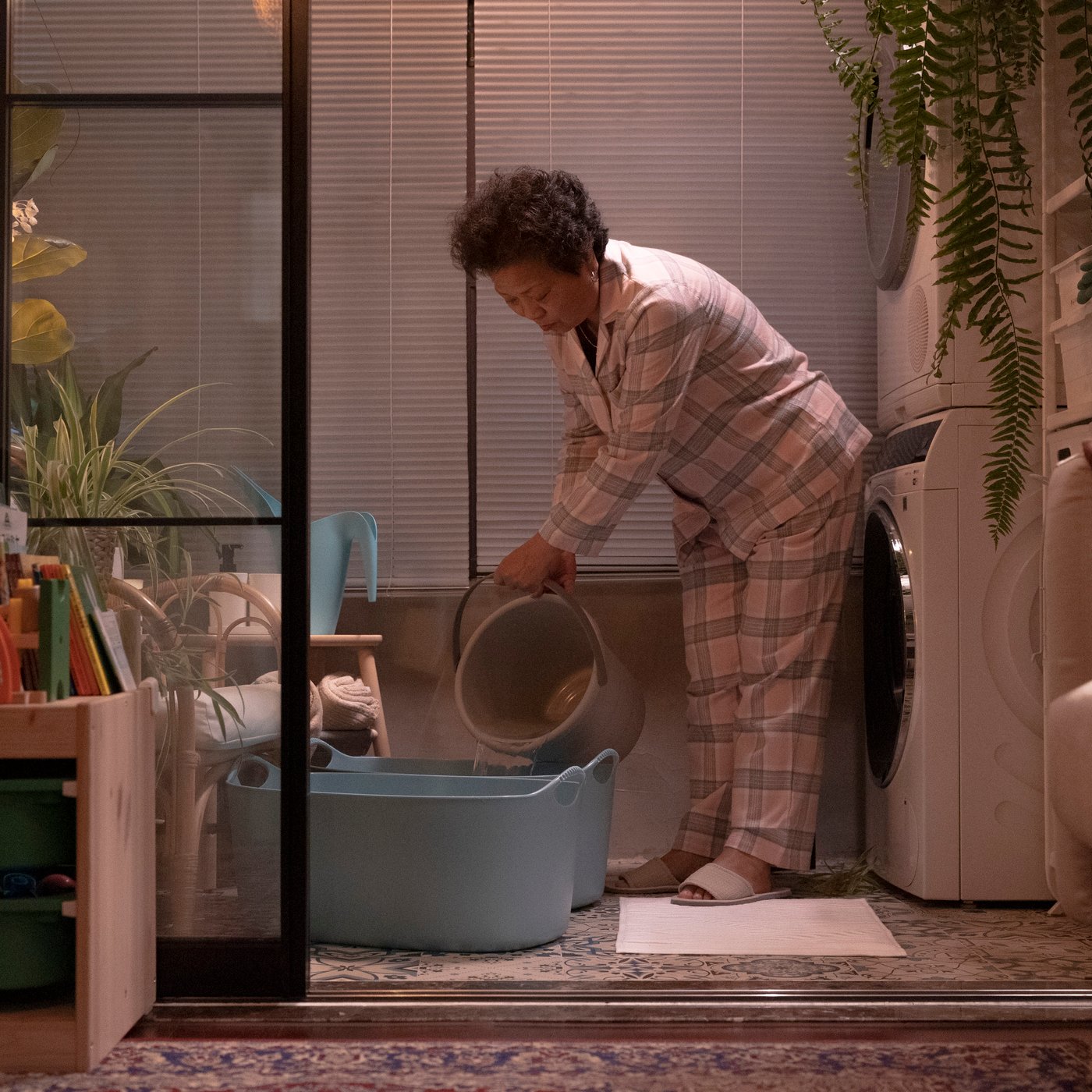 A woman in pyjamas fills up two TORKIS laundry baskets with water.