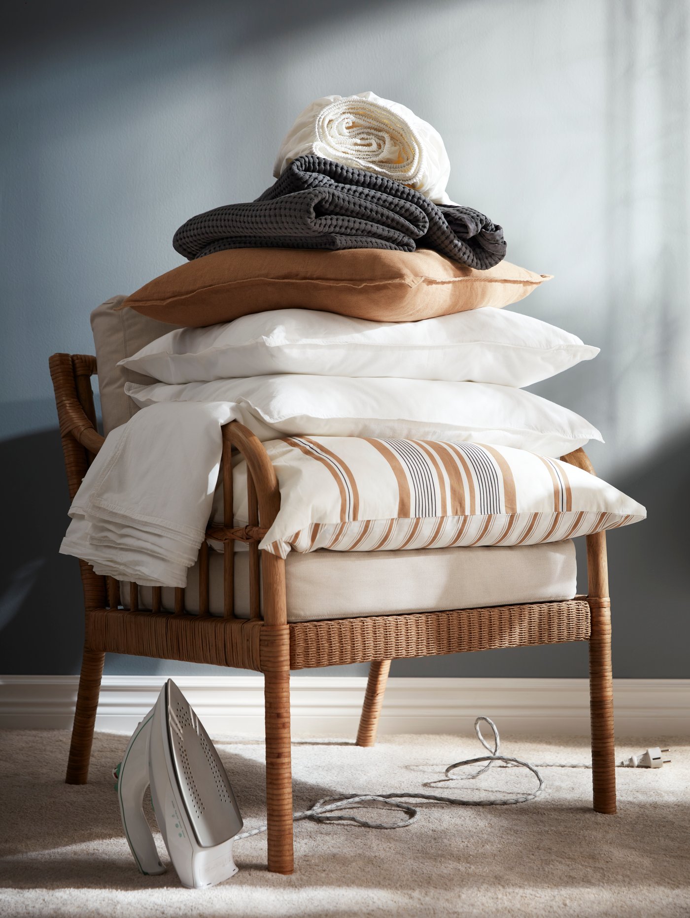 Una silla de madera con ropa de cama apilada en su asiento.