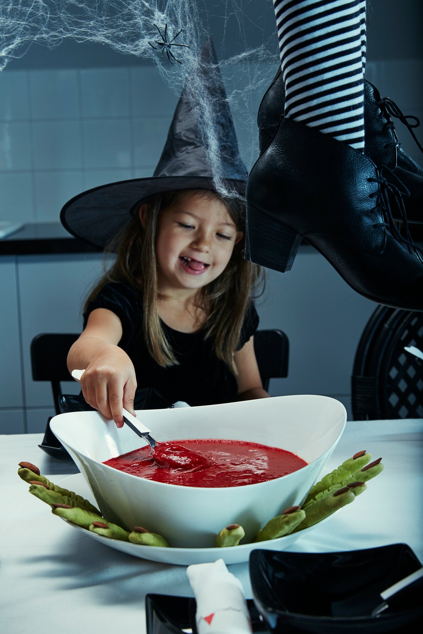 Ein kleines Mädchen schaufelt etwas rote Suppe.