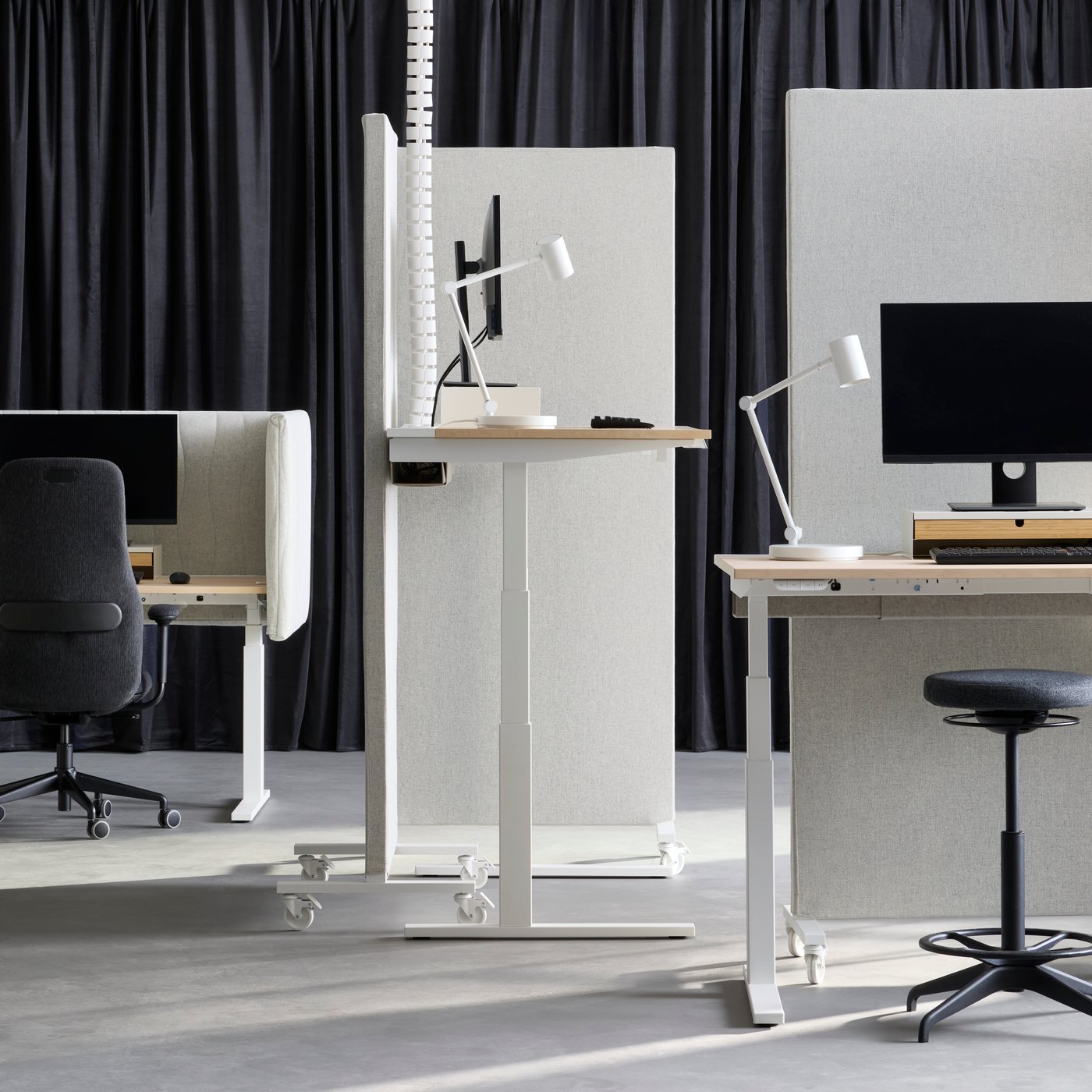 Office space with sit/stand desk workstations, separated by beige-white MITTZON acoustic screens in Gunnared fabric.