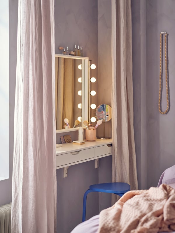 An EKBY ALEX shelf with drawers with a NISSEDAL mirror above that has a MUSIK wall lamp on either side and a stool in front.