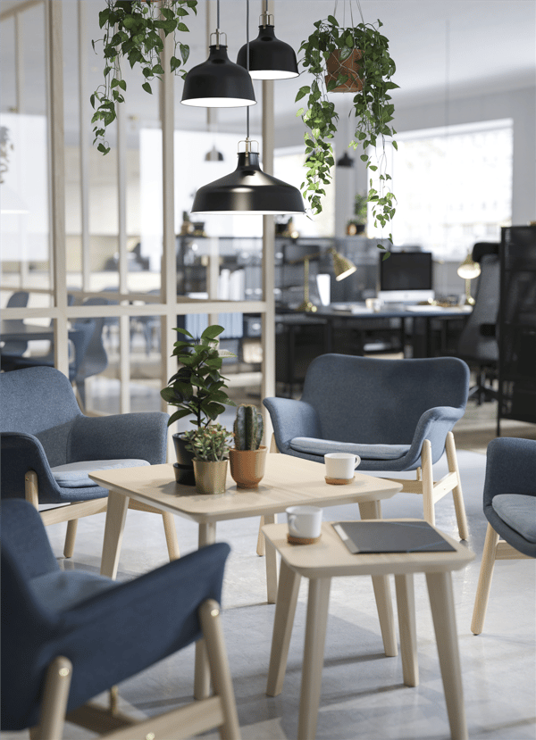 IKEA FOTO pendant lamps, hanging plants, two tables and sloped blue chairs in a waiting area.