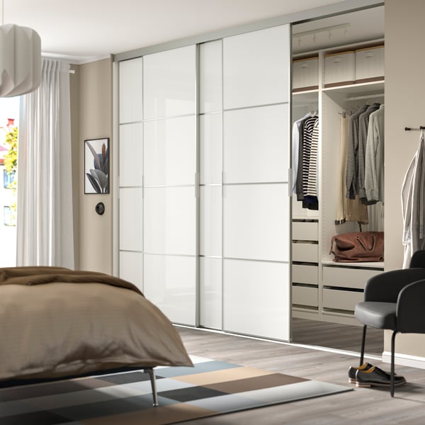 PAX wardrobe with sliding doors FÄRVIK. Located in a beige bedroom. The wardrobe includes both hanging storage and pull-out drawers