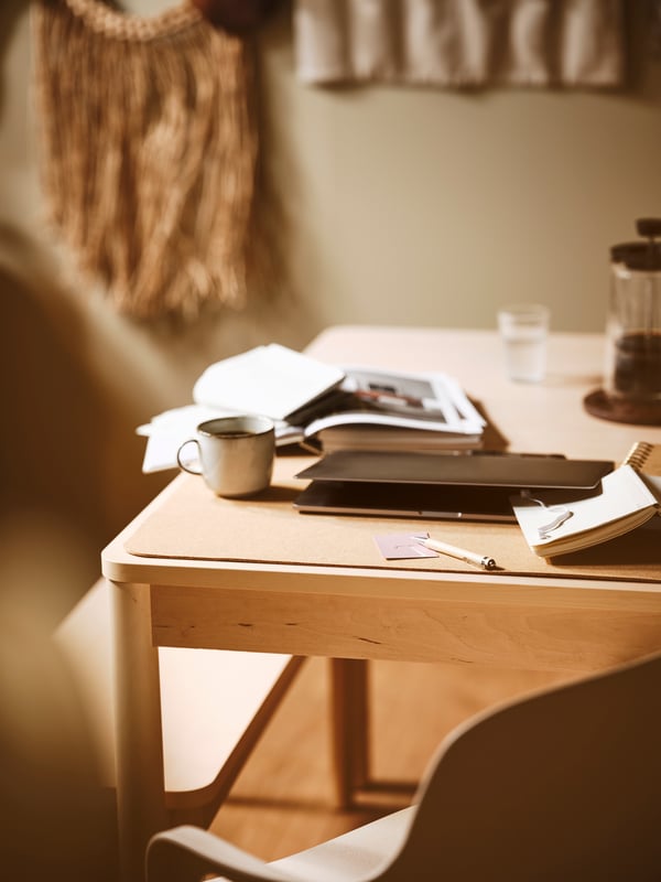 Corner detail of a birch RÖNNINGE dining table with books on top.