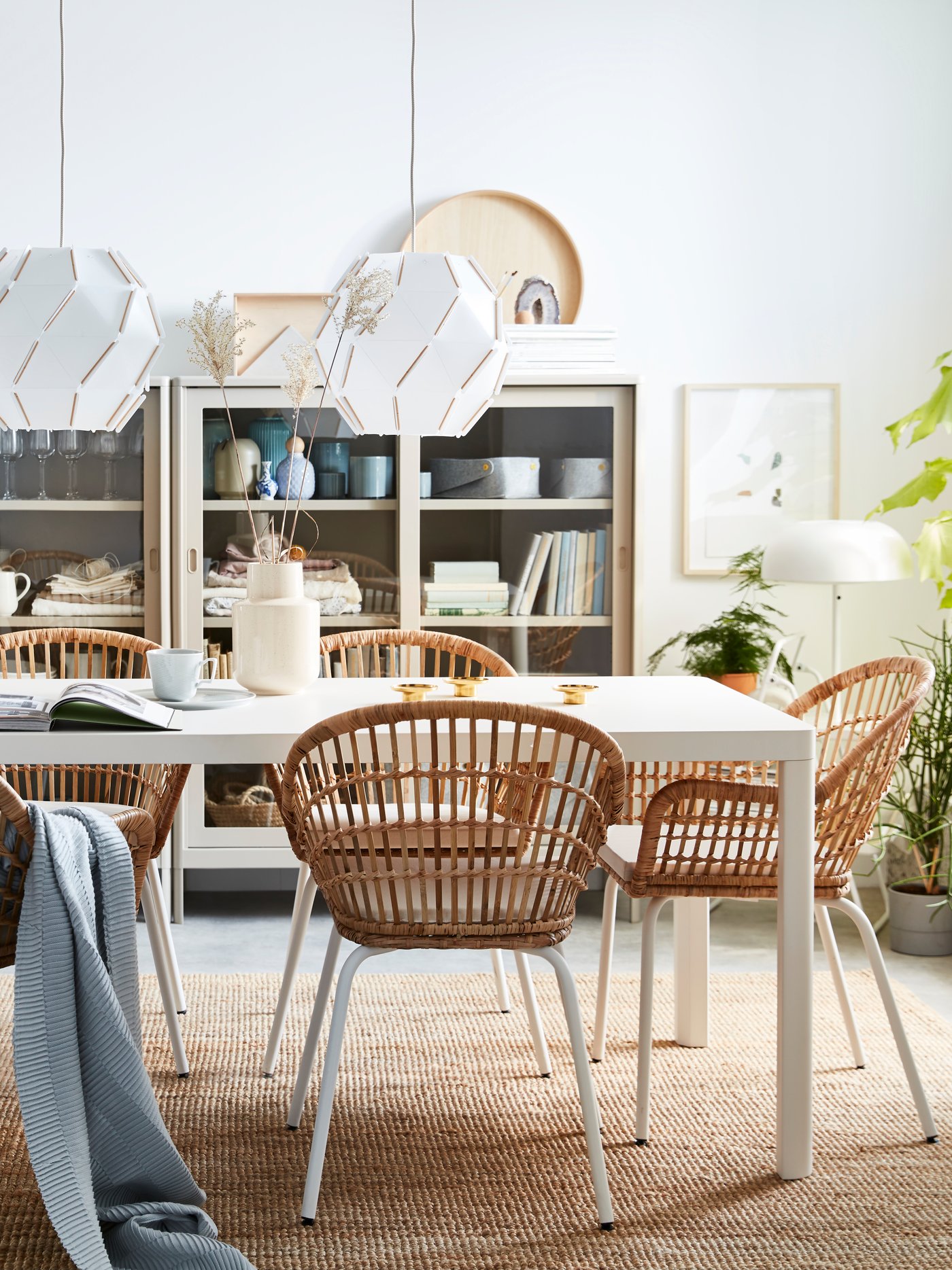 A white TINGBY dining table with rattan white natural NILSOLVE chairs with chair pads in the dining room.
