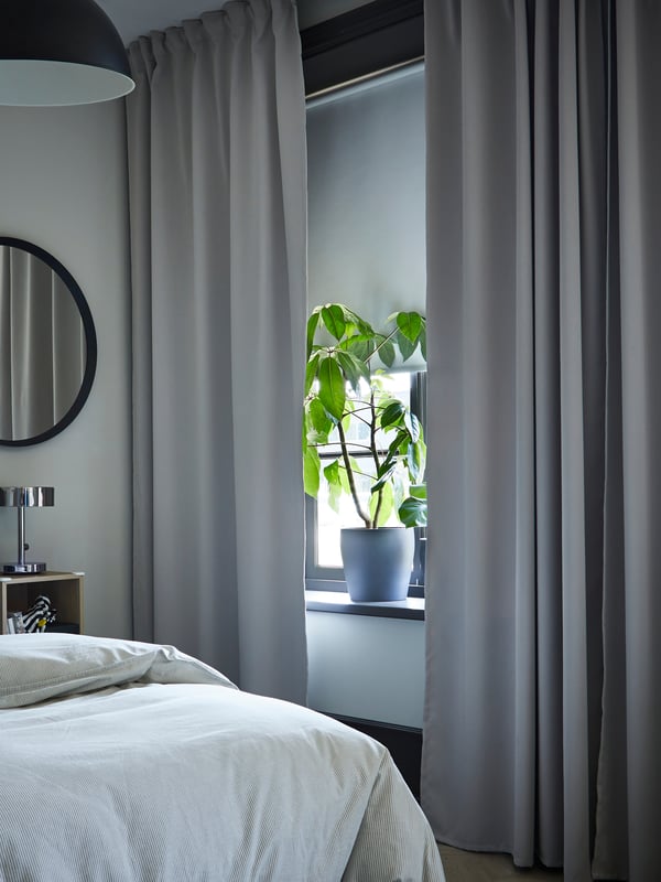 A white FRIDANS block-out roller blind in the bedroom