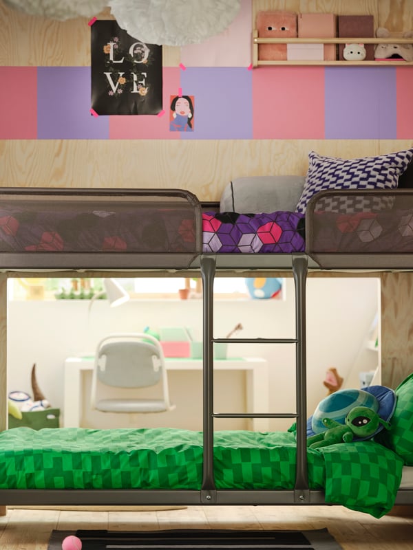 Primo piano di un letto a castello TUFFING con due letti diversi. Accanto al letto in basso c'è una parete divisoria con un foro attraverso il quale si accede a una zona privata.