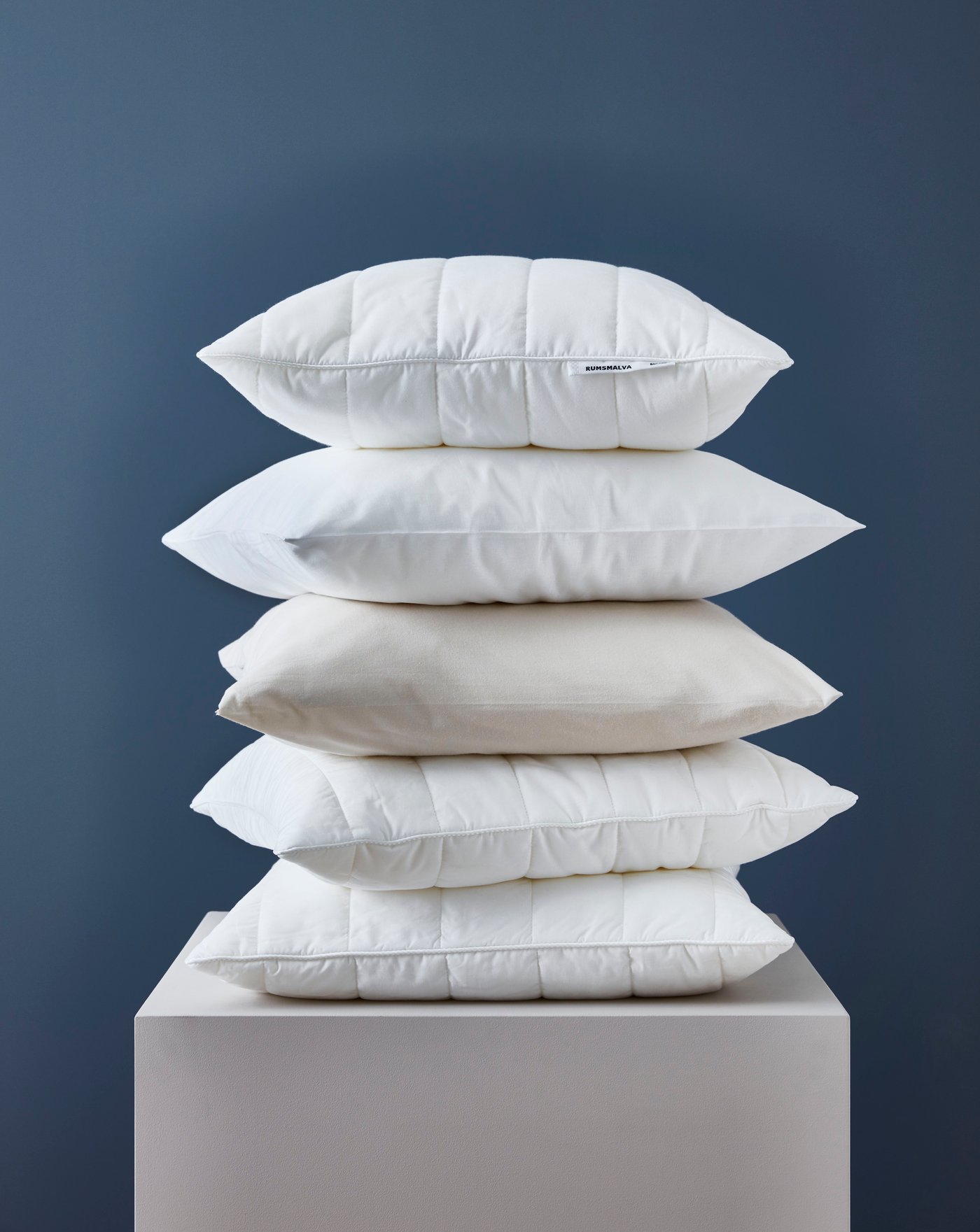 5 almohadas, una sobre la otra sore una mesa IKEA.