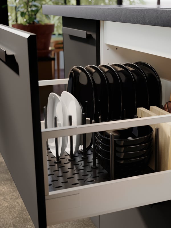 Black and white bowls and plates are neatly stacked in a kitchen drawer with an UPPDATERA pegboard drawer organiser.