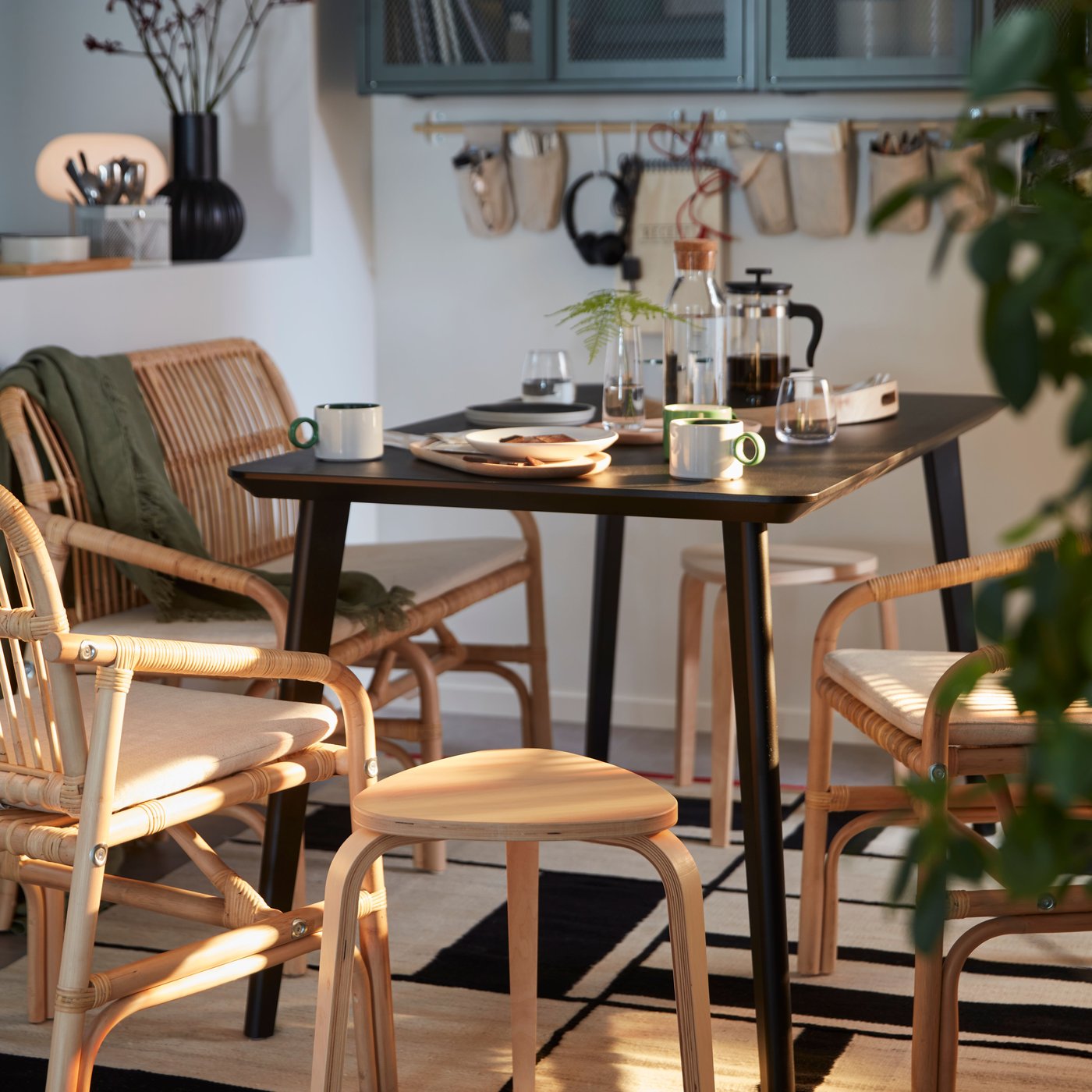 A dining room with a black LISABO dining table and light wood chairs and KYRRE stools.