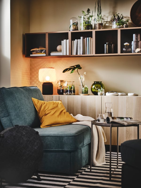 A kellinge grey/turquoise KIVIK sofa-bed stands in a living room by a STARKVIND air purifier and GLADOM tray table.