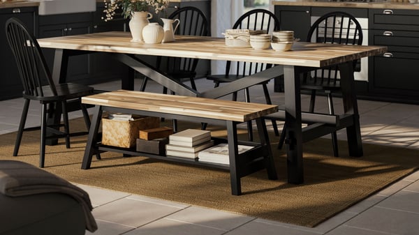 A black SKOGSTA dining bench with storage next to a SKOGSTA dining table in the kitchen.