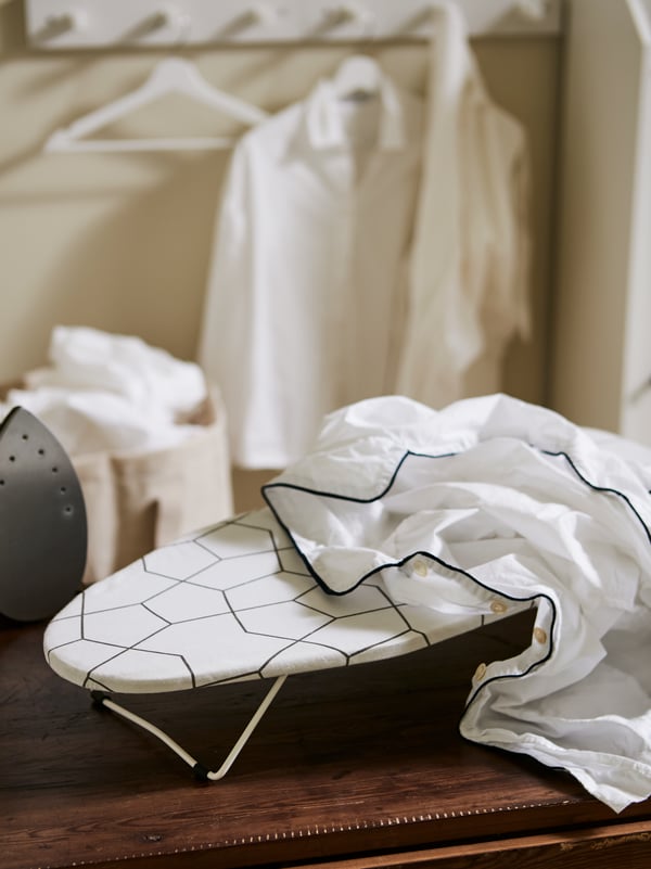 A small ironing board with some laundry on it